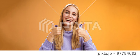 Close-up charming delighted cute female customer give positive feedback show thumbs-up like gesture smiling broadly agree recommend perfect product skincare standing satisfied orange background 97794682