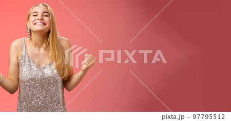 Sweet taste win. Charming happy blond girl rejoicing triumphing raise head up close eyes smiling broadly clench fists victory celebration gesture achieve dream come true, standing red background Sweet taste win. Charming happy blond girl rejoicing triumphing raise head up close eyes smiling broadly clench fists victory celebration gesture achieve dream come true, standing red background 97795512