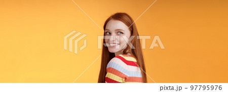 Tender romantic carefree european redhead girlfriend turning behind look left amused smiling pleased coquettish gaze standing orange background flirty romantic mood wanna receive date invitation 97795976
