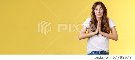Cute hopeful young caucasian girl stooping hold hands pray smiling hope for pity begging favour plead asking advice say sorry grinning lovely making faithful glances you lend hand yellow background Cute hopeful young caucasian girl stooping hold hands pray smiling hope for pity begging favour plead asking advice say sorry grinning lovely making faithful glances you lend hand yellow background 97795978