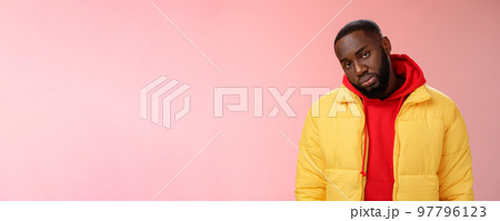 Unimpressed bored ignorant young african bearded man tilt head look scorn uninterest camera listen boring useless information, standing careless in yellow jacket red hoodie, indifferent 97796123