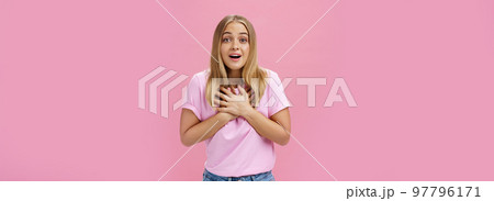 Indoor shot of touched surprised good-looking nice girl in t-shirt and jeans holding palms on heart gasping from amusement and amazement reacting to awesome pleasant news grateful and happy Indoor shot of touched surprised good-looking nice girl in t-shirt and jeans holding palms on heart gasping from amusement and amazement reacting to awesome pleasant news grateful and happy 97796171
