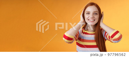 Cute playful tender smiling ginger girl blue eyes silly cover ears palms grinning fool around not hear anyone carefree unwilling listen noisy people standing careless relaxed orange background Cute playful tender smiling ginger girl blue eyes silly cover ears palms grinning fool around not hear anyone carefree unwilling listen noisy people standing careless relaxed orange background 97796562