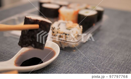 take a roll with chopsticks and dip it in soy sauce take a roll with chopsticks and dip it in soy sauce 97797768