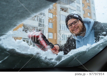 smiling bearded man cleans the car from snow inside view smiling bearded man cleans the car from snow inside view 97797954