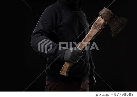 A man in gloves holds an ax in his hands against a black background A man in gloves holds an ax in his hands against a black background 97798088