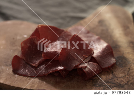 Dried pastrami slices on a wooden board with natural light 97798648