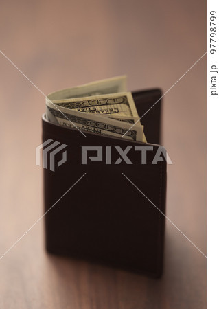 Bespoke brown all leather wallet on walnut table with us dollar cash Bespoke brown all leather wallet on walnut table with us dollar cash 97798799