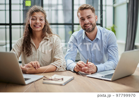 Attractive man and charming woman is pointing at the laptop screen, laughing together, resting 97799970