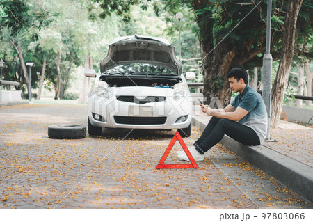 Asian man using smartphone for assistance after a car breakdown on street. Concept of vehicle engine problem or accident and emergency help from Professional mechanic 97803066