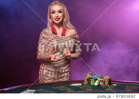 Blonde woman with a perfect hairstyle and bright make-up is posing with gambling chips in her hands. Casino, poker. 97803692