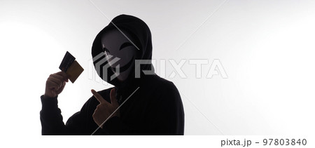 Hacker man and credit cards in hand. Represent credit cards personal data stolen by anonymous man in Black hood shirt. Credit cards data security and Cyber crime digital. Money transection unsecured. 97803840