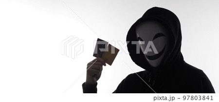Hacker man and credit cards in hand. Represent credit cards personal data stolen by anonymous man in Black hood shirt. Credit cards data security and Cyber crime digital. Money transection unsecured. 97803841