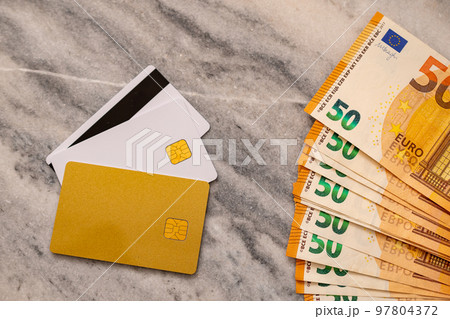Close-Up Part Of 50 Euro Banknotes And Bank cards. Concept Of Comparing Cash And Non-Cash Money. Close-Up Part Of 50 Euro Banknotes And Bank cards. Concept Of Comparing Cash And Non-Cash Money. 97804372