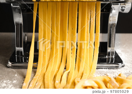 Pasta maker machine with dough on grey table, closeup 97805029