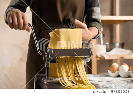 Woman preparing noodles with pasta maker machine at table indoors, closeup Woman preparing noodles with pasta maker machine at table indoors, closeup 97805033