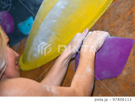 The girl goes in for sports on the climbing wall in the hall, close-up 97806113