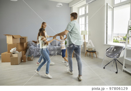 Cheerful young family with children dancing and having fun while moving to new apartment. 97806129
