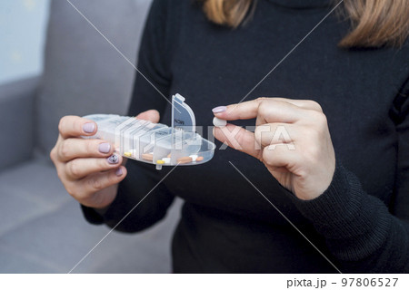 Woman taking medication from pill box. Health care and treatment concept 97806527