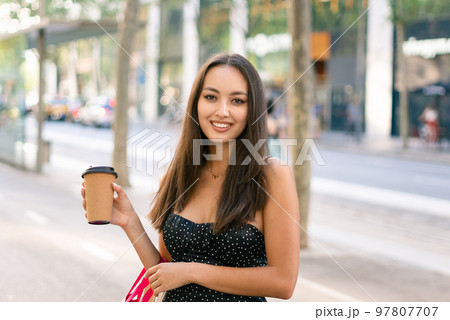 Cheerful female shopper with takeaway coffee Cheerful female shopper with takeaway coffee 97807707