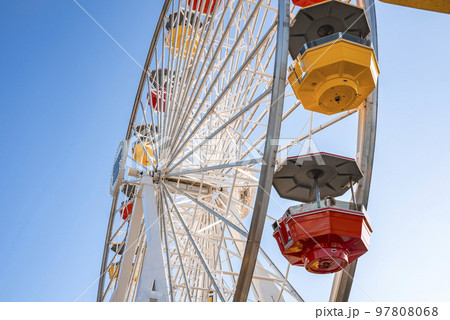 Low angle view of of colorful ferris wheel with clear blue sky in background during summer season at Pacific Park on Santa Monica Pier at Los Angeles 97808068