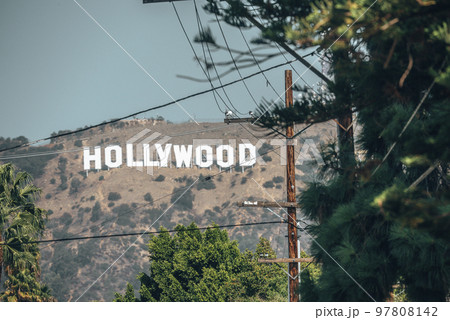 Los Angeles, USA. September 20, 2022. Distant view of Hollywood sign on beautiful Mount Lee seen through electricity pole and trees with sky in background during sunny day 97808142
