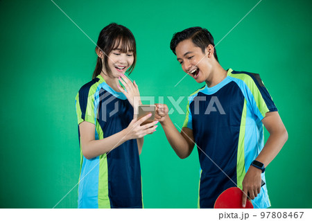 female and male athletes happily looking at smartphones together 97808467