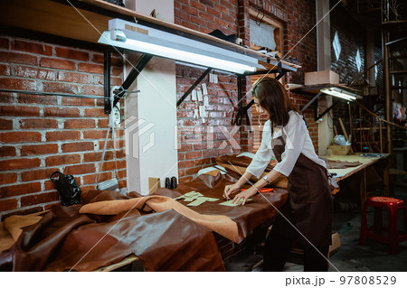 Young asian craftswoman working at desk in leather fabric 97808529