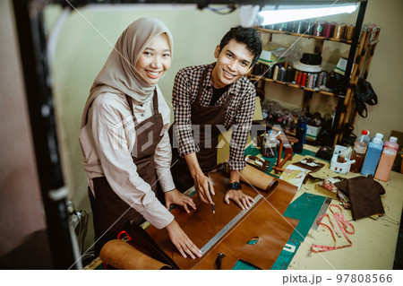 craftsman and craftswoman in hijab smiling at the camera 97808566