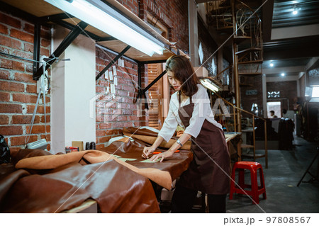 Tailor in apron working measuring leather material in leather workshop Tailor in apron working measuring leather material in leather workshop 97808567