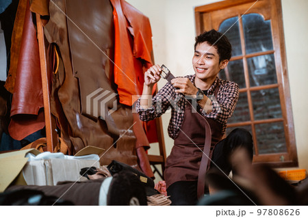 smiling craftsman holding a leather belt in a tannery workshop 97808626