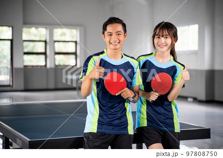 Two smiling asian athletes holding paddle with thumbs up Two smiling asian athletes holding paddle with thumbs up 97808750