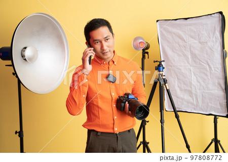 photographer holding professional camera while making phone call photographer holding professional camera while making phone call 97808772