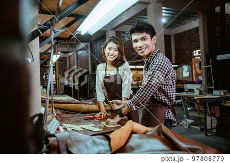 Asian male and female leather worker smiling in his studio 97808779