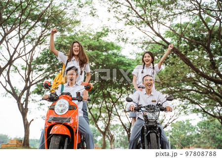Two pairs of high school students celebrate graduation by motorbikes 97808788