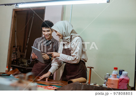 female tailor in veil and male tailor using pad female tailor in veil and male tailor using pad 97808803