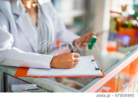close up of pharmacist working writing drug list with pen and clipboard 97808995