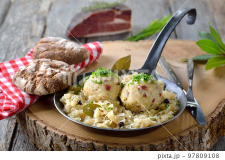 Delicious South Tyrolean bacon dumplings served on sauerkraut in an iron frying pan Delicious South Tyrolean bacon dumplings served on sauerkraut in an iron frying pan 97809108