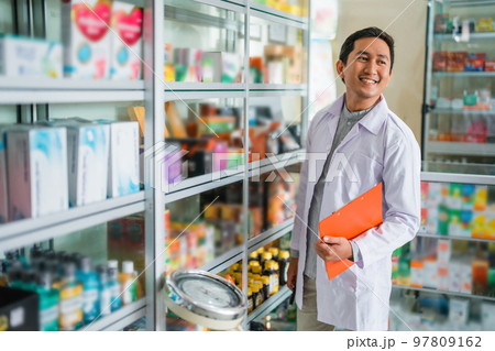 male pharmacist in uniform looking up while holding clipboard standing 97809162