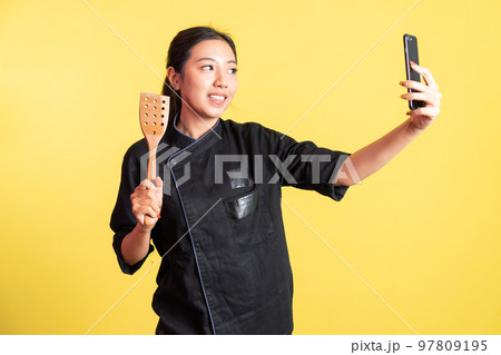 female chef selfie using mobile phone and hand holding spatula female chef selfie using mobile phone and hand holding spatula 97809195