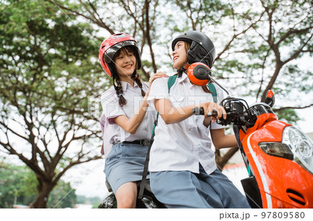 Two girls chatting while riding a motorcycle together 97809580