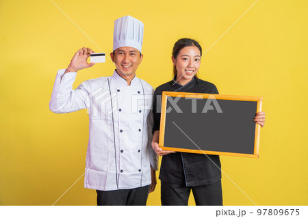 two asian chefs holding atm cards and showing blank blackboard two asian chefs holding atm cards and showing blank blackboard 97809675