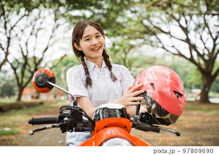 Beautiful student girl smiling while taking off her helmet 97809690