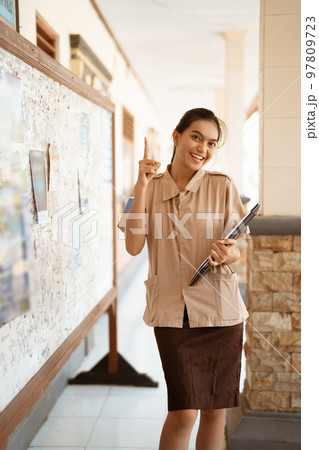 excited asian high school student with pointing finger holding laptop excited asian high school student with pointing finger holding laptop 97809723