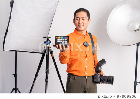 photographer holding color palette while carrying camera with lighting equipment 97809806