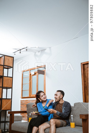 beautiful girl feeds a snack to boyfriend on the sofa beautiful girl feeds a snack to boyfriend on the sofa 97809882
