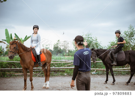 two equestrian athletes riding horses listening to trainer standing guide 97809883