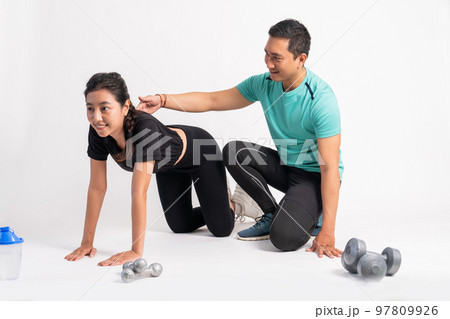 woman with basic push up movement with trainer holding back woman with basic push up movement with trainer holding back 97809926