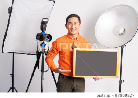 photographer standing with pointing hand while holding blackboard photographer standing with pointing hand while holding blackboard 97809927