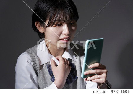 暗闇でスマホを見て悩む女子高生 97811601